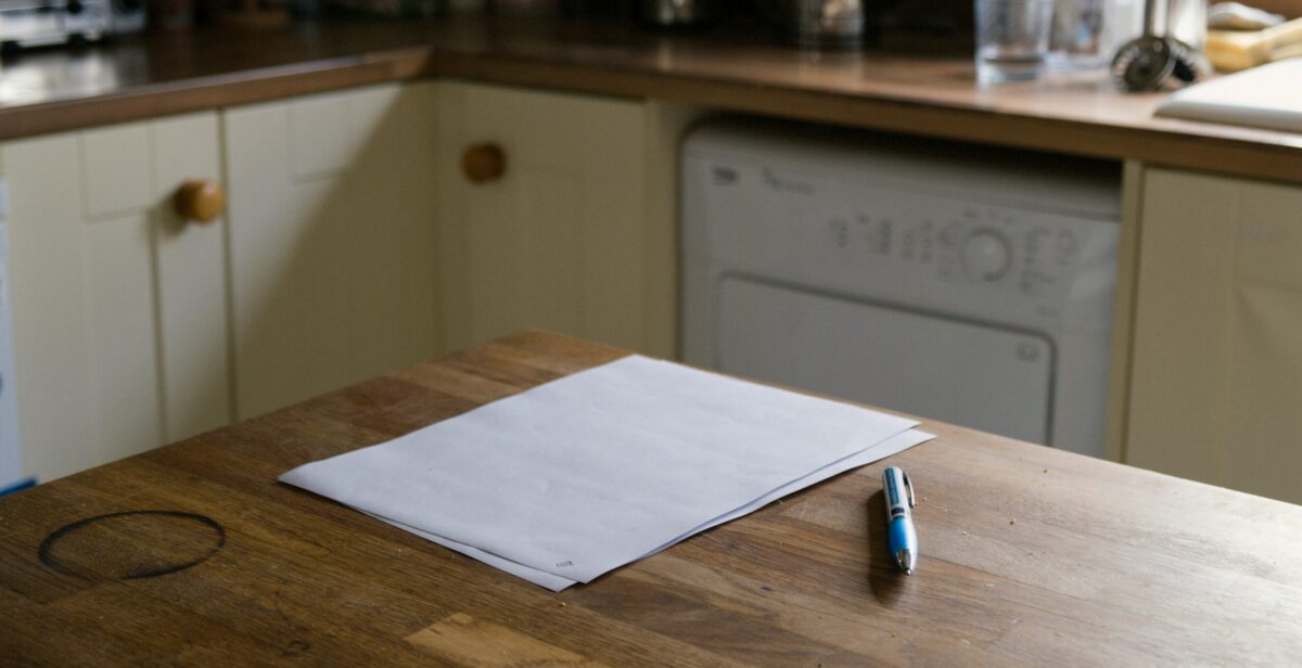 Photo image of a kitchen table, with a pile of paper on top